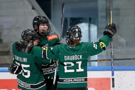 Drei Eishockeyspielerinnen jubeln gemeinsam in eine Eishalle.