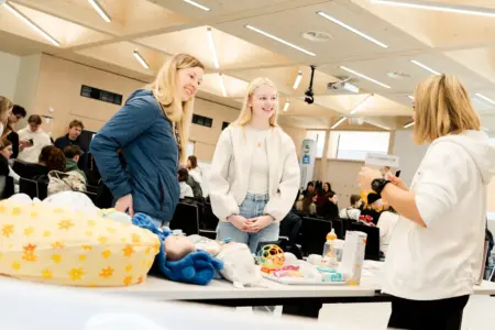 Drei Frauen an einem Informationsstand in einem großen Raum
