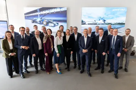 Rund 20 Personen in Businesskleidung in einem Konferenzraum