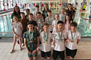 Ein Gruppe von Kindberg und Jugendlichen mit vielen Medaillen in einem Hallenbad.