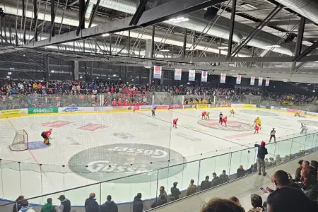Eine Eishalle mit zahlreichen Zusehern und Eishockeyspielern auf dem Eis.