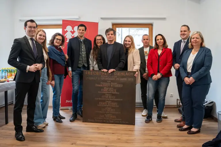 Eine Gruppe von Personen mit einer Gedenktafel in einem großen Raum