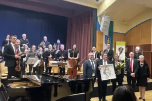 Eine Gruppe von Musikern und wetere Personen stehen auf und vor einer Bühne