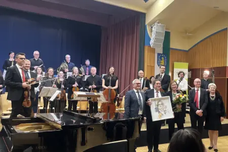 Eine Gruppe von Musikern und wetere Personen stehen auf und vor einer Bühne