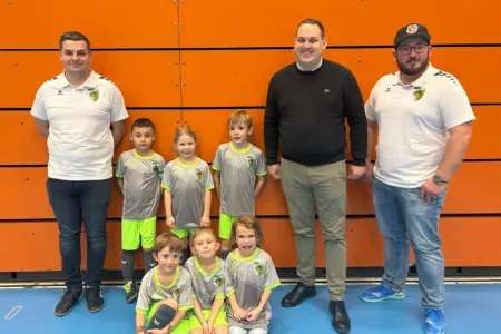 Drei Männer und sechs Kinder stehen bzw. sitzen vor einer Wand.