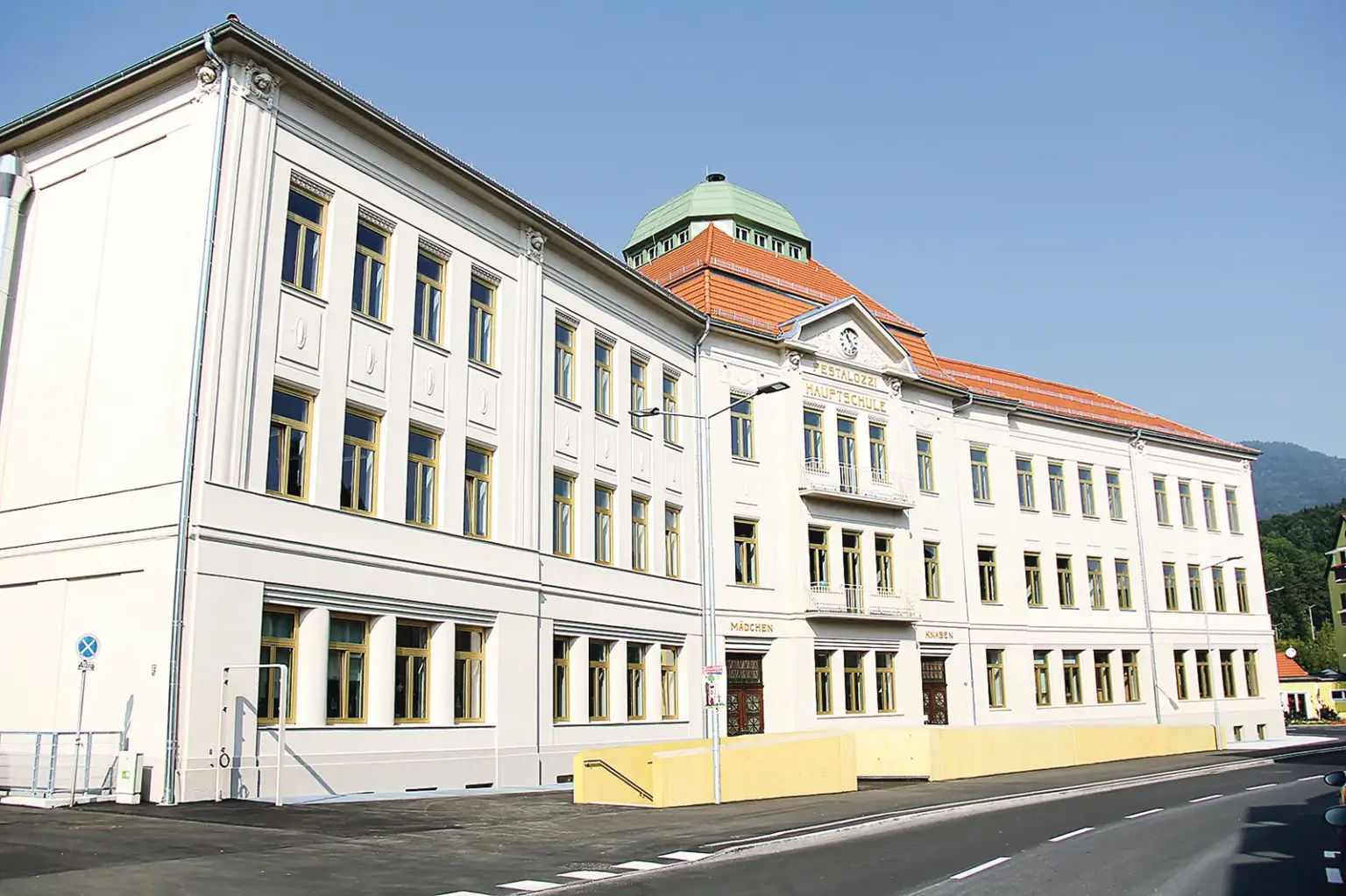 Ein dreigeschoßiges Schulgebäude mit renovierter Fassade und Dachkuppel