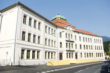 Ein dreigeschoßiges Schulgebäude mit renovierter Fassade und Dachkuppel
