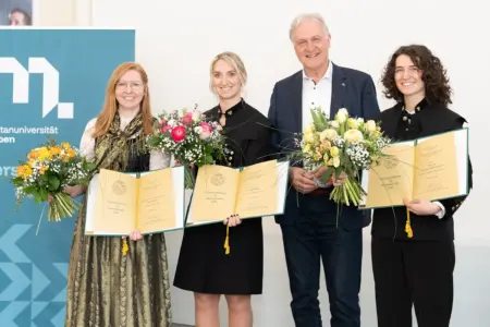 Ein Mann und drei Frauen mit Urkunden und Blumensträußen