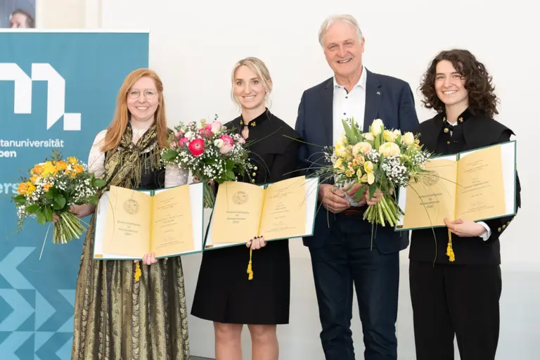 Ein Mann und drei Frauen mit Urkunden und Blumensträußen