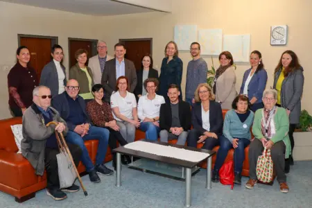 Eine größere Gruppe von Personen rund um eine Sitzgruppe