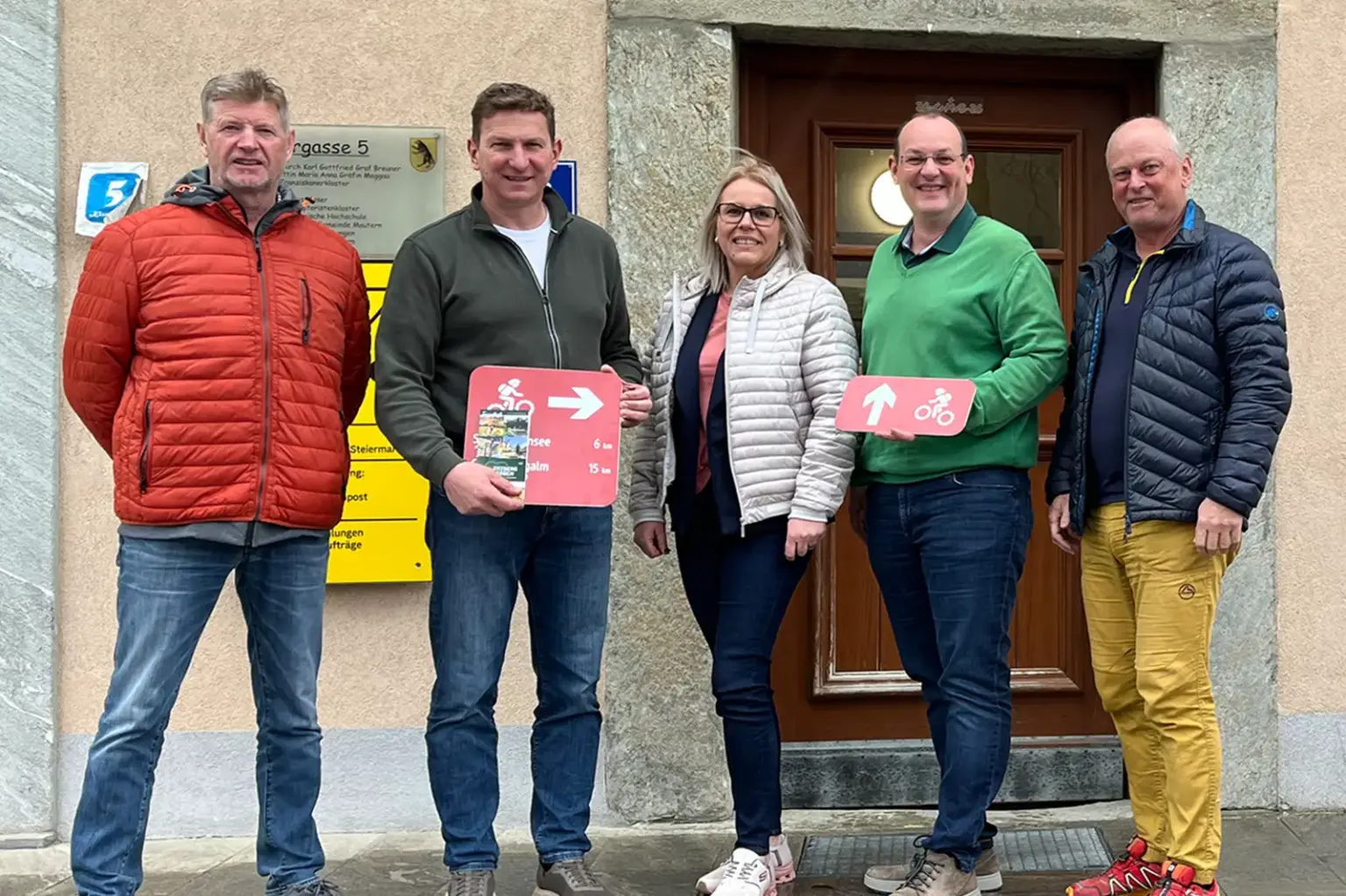 Vier Männer und eine Frau stehen vor einem Haus