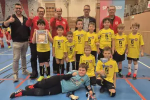 Eine Gruppe von Kindern in gelben Trikots, dahinter stehen mehrere Erwachsene.