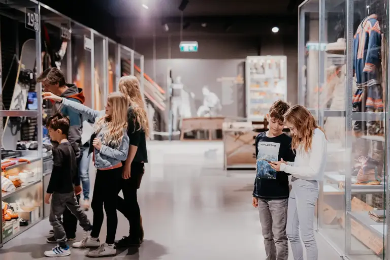 Mehrere Kinder und Erwachsene in einem großen Raum mit Vitrinen und Schautafeln