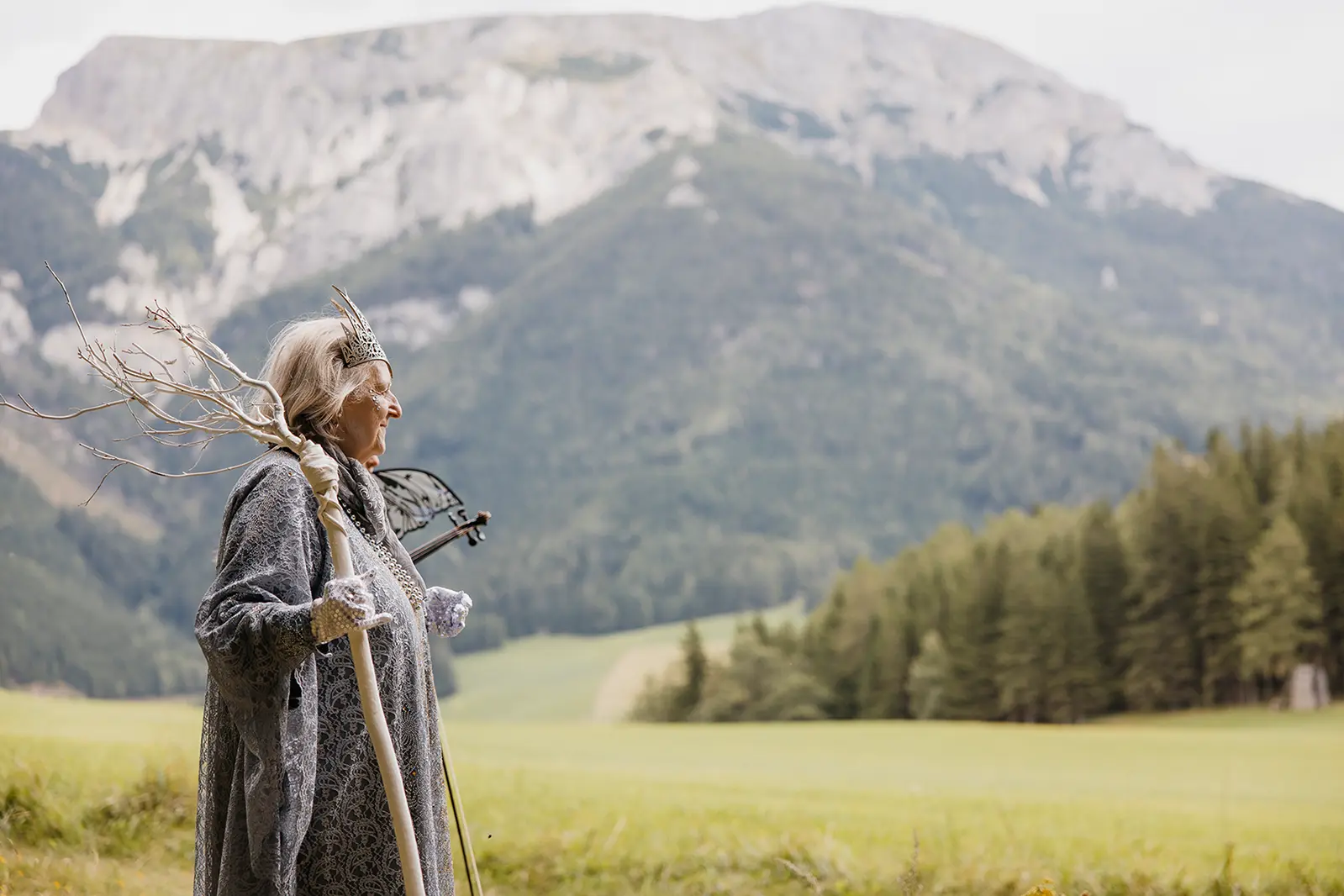 Eine alte Frau in einem Fantasy-Kostüm vor einem Berg