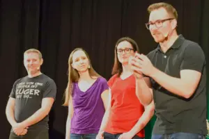 Zwei Männer und zwei Frauen stehen vor einem schwarzen Vorhang