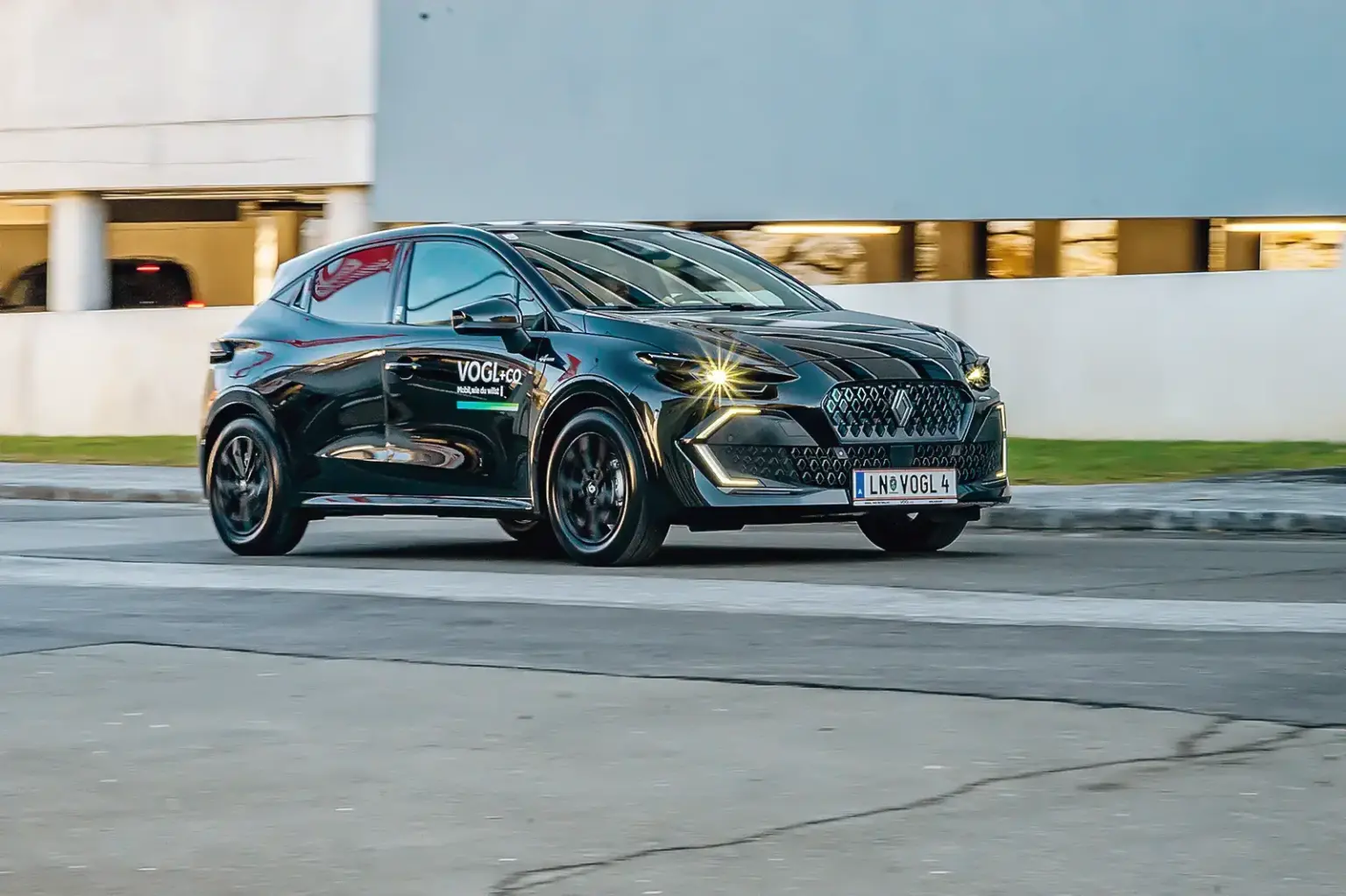 Von der Muse geküsst Ein schwarzes Auto der Kompaktklasse fährt auf einer Straße von links nach rechts, im Hintergrund eine Betonwand