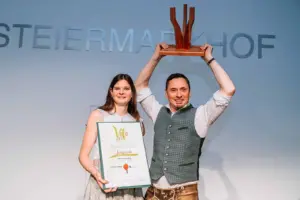 Ein Mann und eine Frau halten eine Urkunde und eine Trophäe