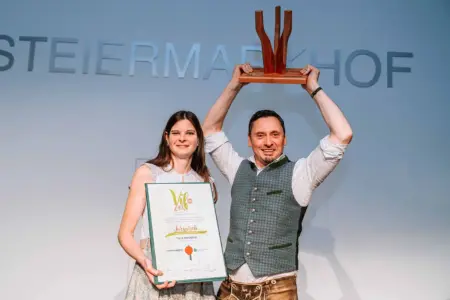 Ein Mann und eine Frau halten eine Urkunde und eine Trophäe