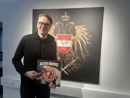 Napalm Records: Ein Leben für den Heavy Metal Ein Mann mit Schallplatte vor einem Bild mit dem Logo der Firma Napalm Records.