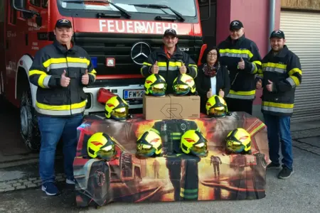 Neue Helme für die Feuerwehr Steinhaus Vier Männer in Uniform und eine Frau hinter einem Tisch voller gelber Helme
