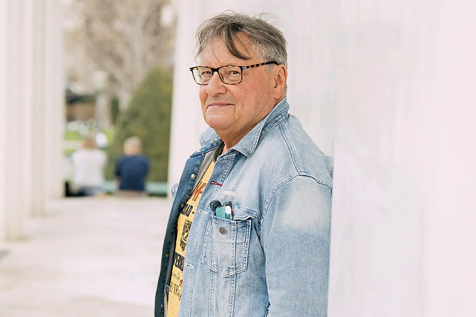 Ein Mann in Jeansjacke lehnt an einer Wand