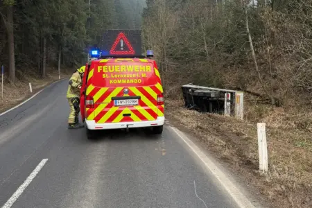 Ein Feuerwehrauto steht auf der Straßen, neben im Flussbett liegt ein Aufleger eines Sattelschleppers.