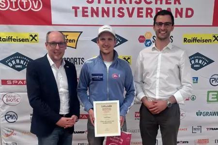 Drei Männer stehen nebeneinander, der mittlere hat eine Urkunde in der Hand.