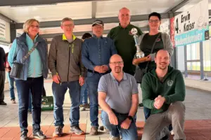 Sieben Personen in einer großen Halle mit einem Pokal