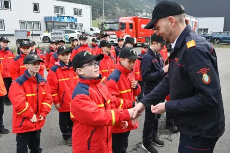Ein Mann in Uniform gratuliert einer großen Gruppe von Kindern und Jugendlichen in roten Jacken