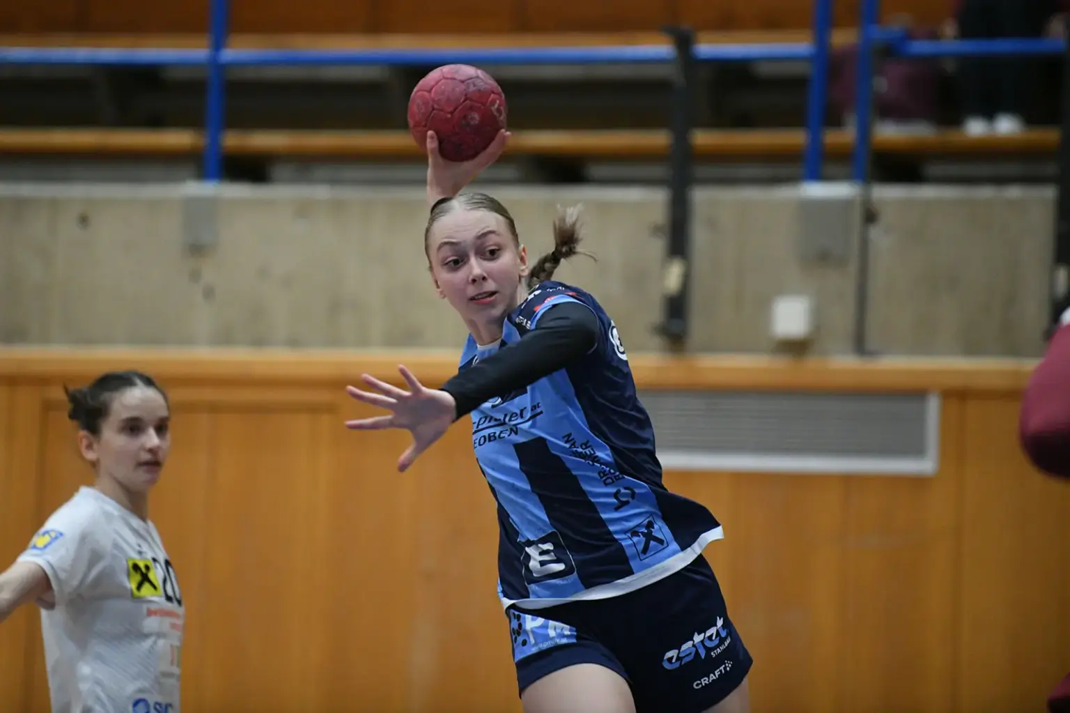Eine Frau wirft einen Handball in einer Sporthalle.