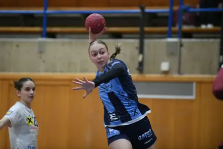 Eine Frau wirft einen Handball in einer Sporthalle.