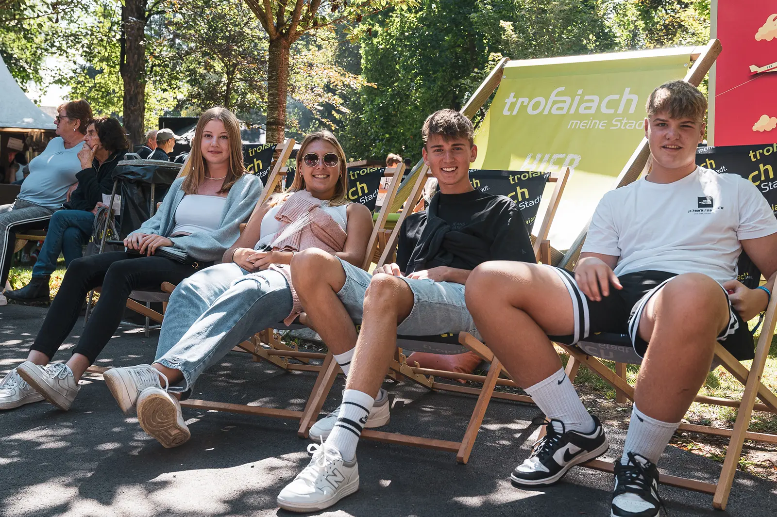 Eine Grupper junger Menschen sitzt in Klappstühlen im Grünen