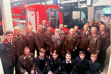 Eine große Gruppe von Personen verschiedenen Alters in Uniform vor einem Feuerwehrauto