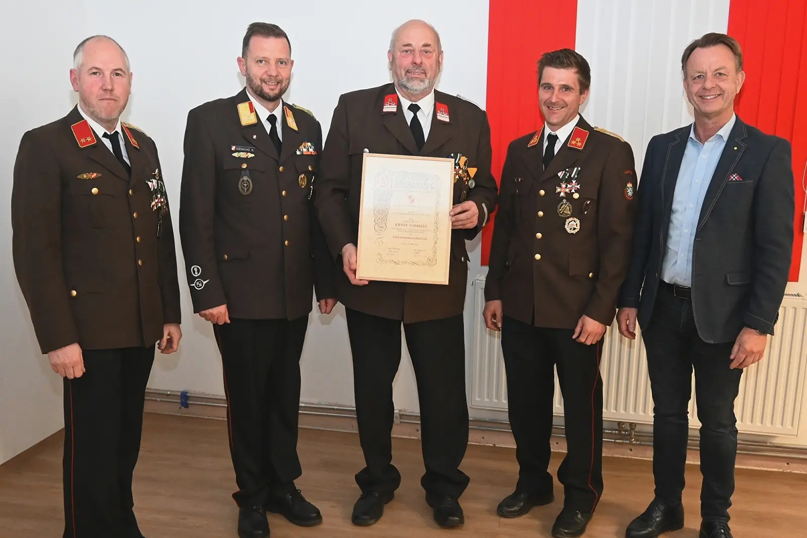 Vier Männer in Uniform und ein weiterer Mann zeigen eine Urkunde