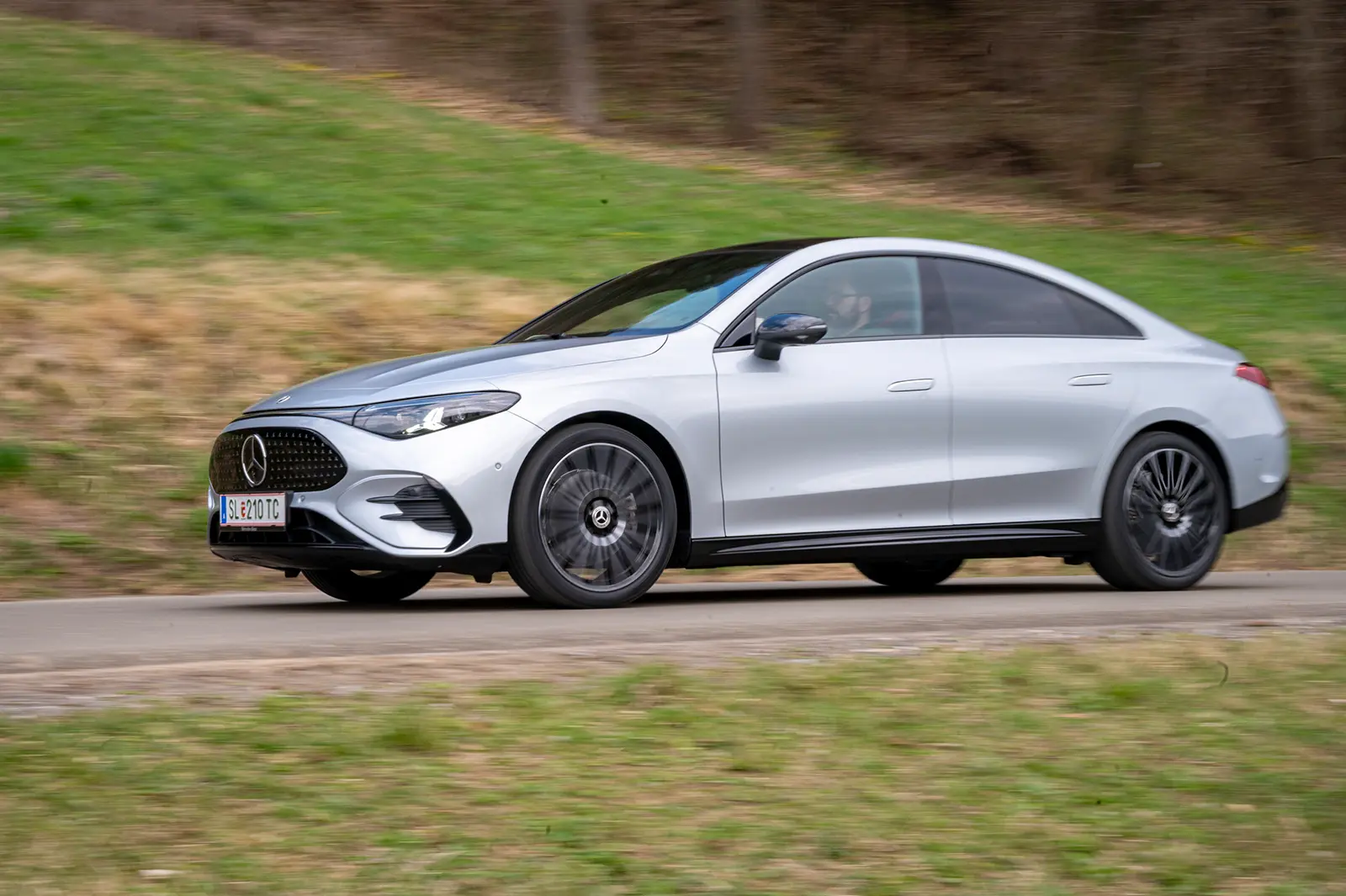 Ein silbergraues Coupé fährt auf einer Landstraße