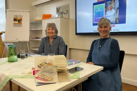 Zwei Frauen sitzen an einem Tisch mit Büchern