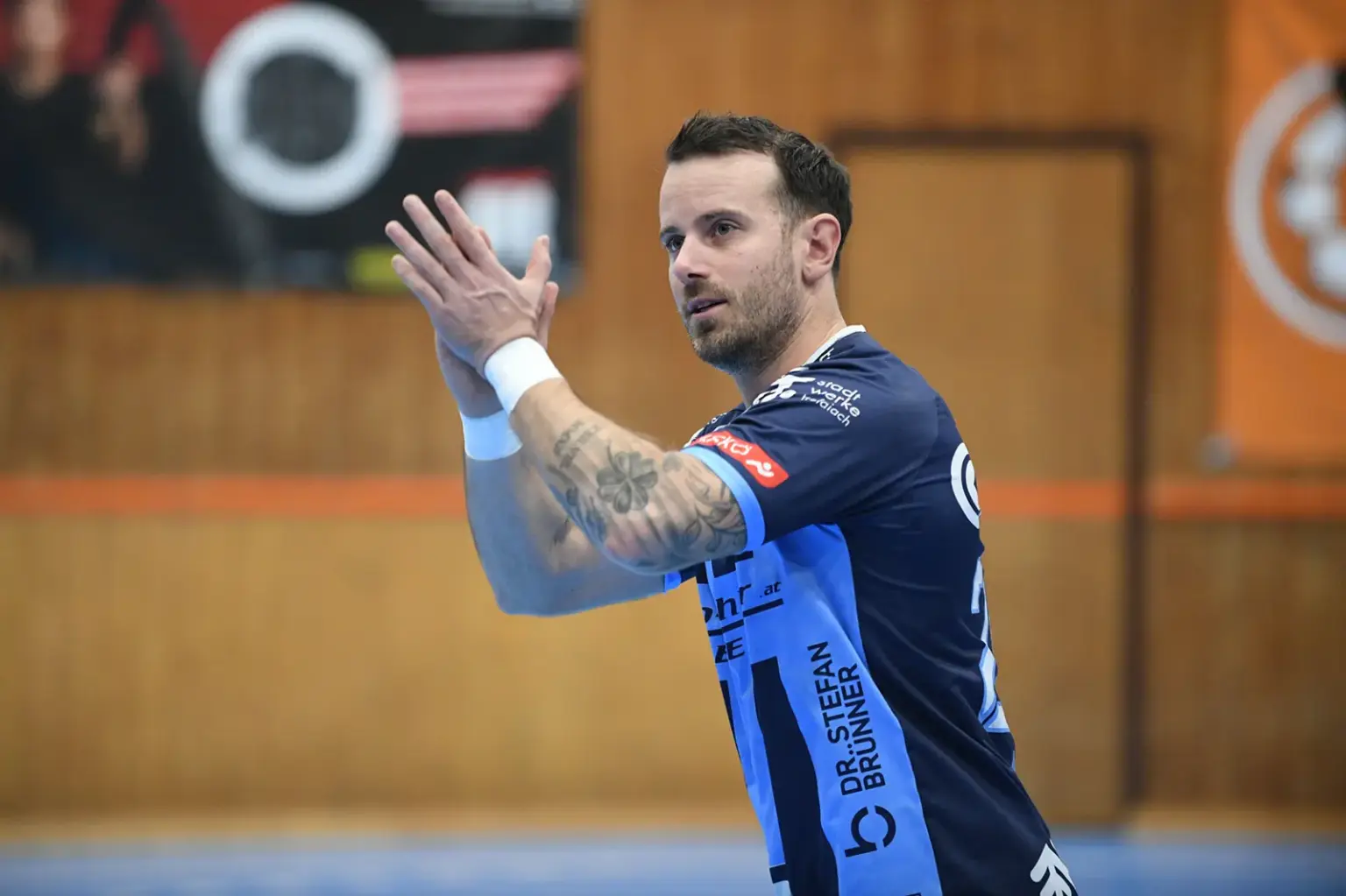 BT Füchse treffen im Viertelfinale auf Linz Ein Handballspieler in blauem Trikot klatscht während eines Spiels in einer Sporthalle in die Hände.
