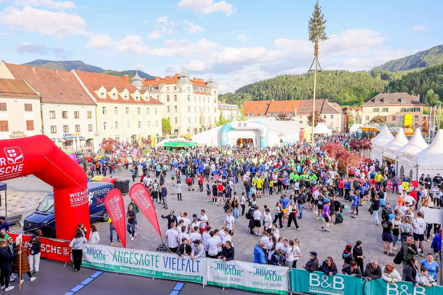 Viele Personen stehen auf einem großen Platz mit mehreren Zelten