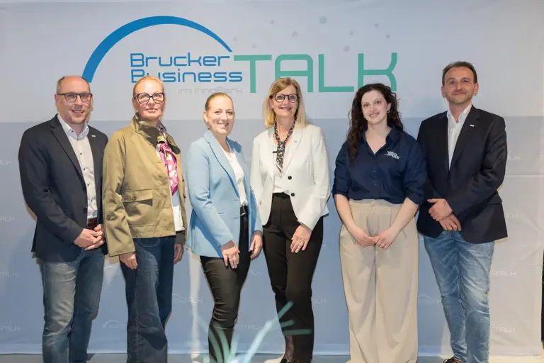 Drei Männer und drei Frauen stehen vor einer Wand