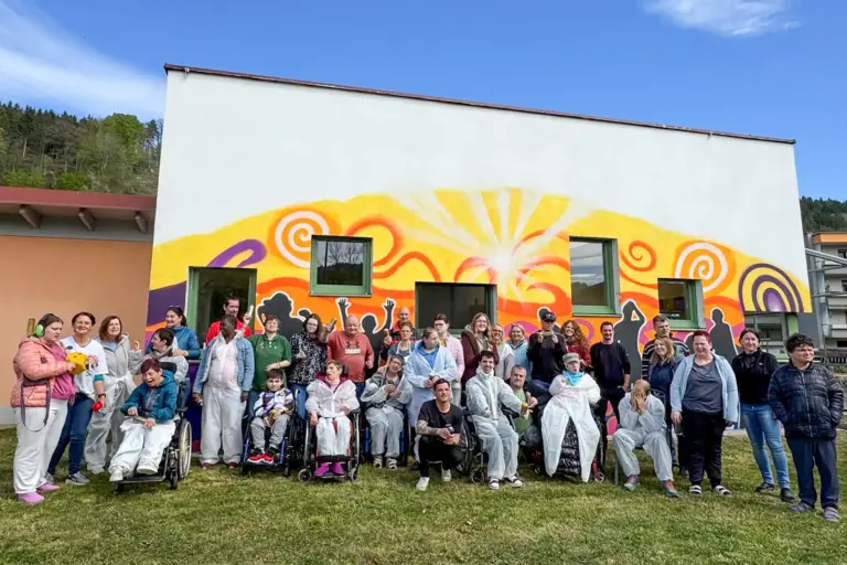 Eine Gruppe von Personen steht vor einer bunten Wand