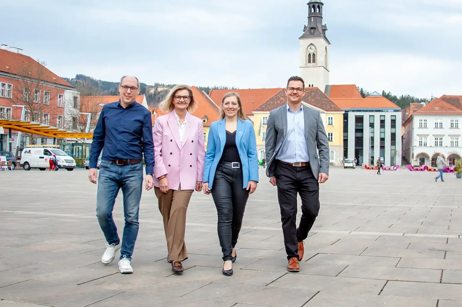 Zwei Frauen und zwei Männer gehen nebeneinander über einen innerstädtischen Platz