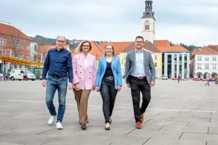 Zwei Frauen und zwei Männer gehen nebeneinander über einen innerstädtischen Platz