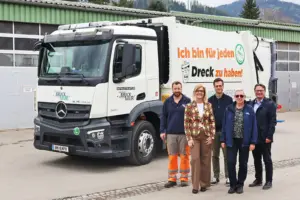 Drei Männer und zwei Frauen stehen neben einem Müllfahrzeug