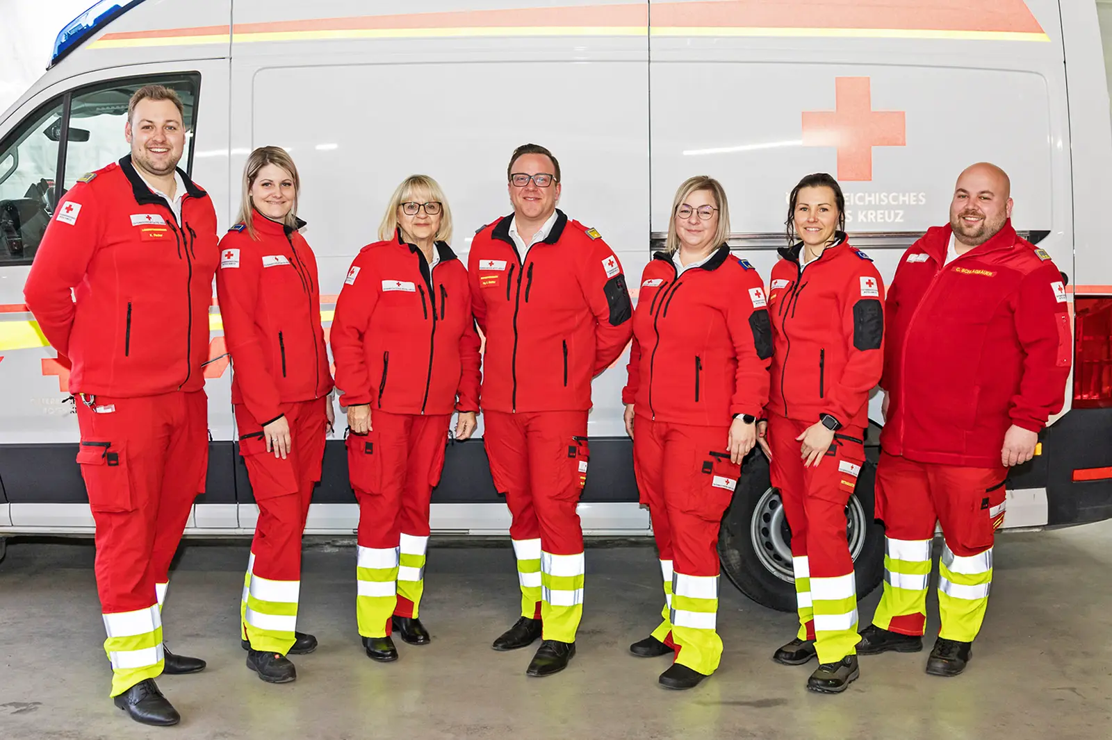 Sieben Personen in Uniform stehen vor einem Rettungswagen