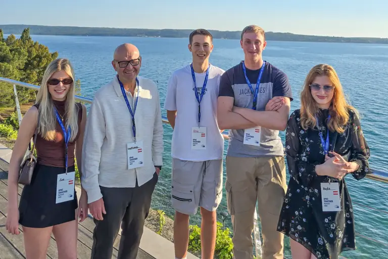 Ein älterer Mann und vier Jugendliche stehen am Meer