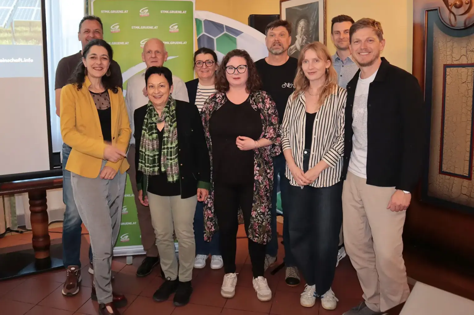 Zehn Personen stehen neben einer Leinwand