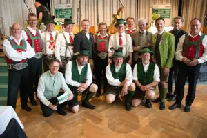 Eine große Gruppe von Männern in Tracht steht vor einer Bühne
