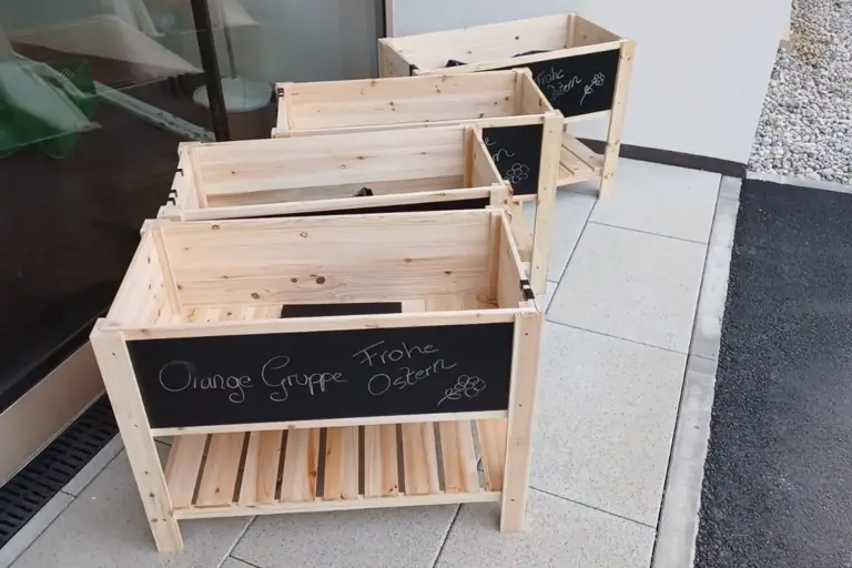 Vier Hochbeete aus Holz stehen vor einer Türe