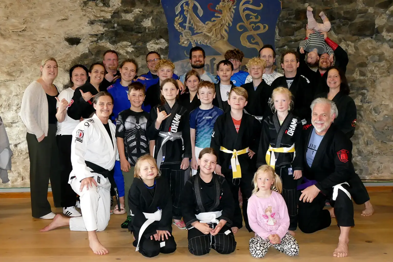 Eine Gruppe von Personen in Sportkleidung posiert vor einem Wappen