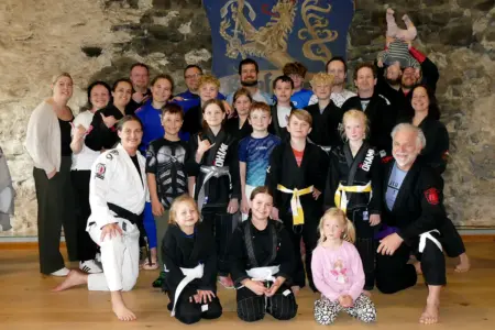 Eine Gruppe von Personen in Sportkleidung posiert vor einem Wappen